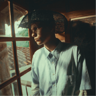 Hombre joven con sombrero mirando por una ventana